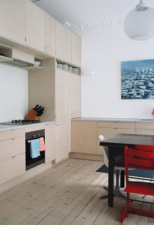 Budget-Friendly Renovation of a Neoclassical Home in Oslo - Photo 4 of 11 - Planning more storage was critical. "We used custom fir plywood doors to make the Ikea cabinets under the marble countertops special," Lexie says of the kitchen. Joining simple white chairs around the dining table are red Tripp Trapp high chairs from Stokke—the same model Casper had as a child.