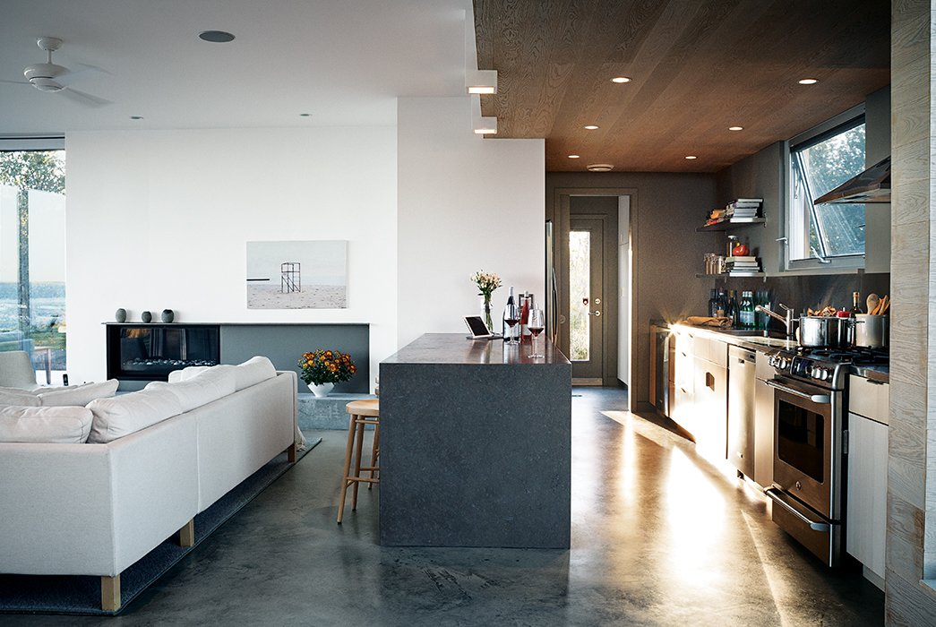 The cabinets are from Ikea, the range is by GE, and the Jenn-Air refrigerator is tucked unobtrusively into the pantry wall. The troweled concrete floor was poured in place by the builder, Peter Knudsen.