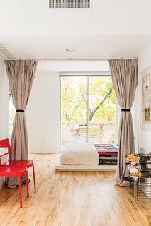 The sleeping space is set off with curtains instead of a door to foster an open feel on the ground floor. Bedding from West Elm and a quilt made by Magill’s mother sit atop a platform bed, also from West Elm. The red chairs, originally from Ikea, were another inexpensive secondhand acquisition. The deck chairs feature reversible canvas slings by the fashion designer Julie Brown.