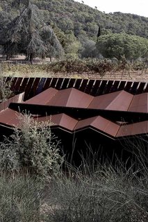 The physical structure is integrated into the natural landscape, and is oriented toward a view of a permaculture vineyard. All wine and produce served to visitors is grown on the estate.