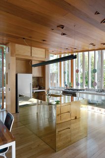 The reflectivity of the brass kitchen island makes it seem to dematerialize.