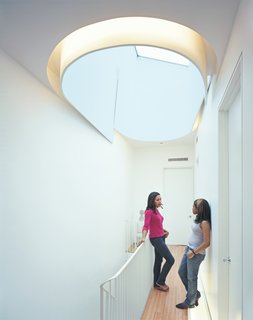 Keisha Martin and her cousin, Mickeda, chat underneath the house’s crowning glory, the oculus, which allows light to spill onto each floor of the house.