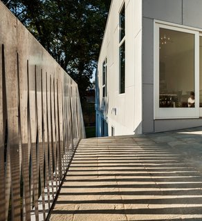 An aluminum water-jet cut fence divides separates the house from its neighbors."My favorite part of the courtyard," says Höweler. He and Meejin took one sheet of metal and cut it down the middle in a zig-zag pattern. "It produces a 'screen' look and creates beautiful shadows. I like that it is materially efficient—there is zero waste of material since both sides of the sheet are used."