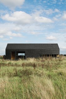 A Pair of English Barns Hide Unabashedly Bold and Budget-Friendly Minimalist Interiors - Photo 2 of 14 - "It only cost about $48,000 to build, which was incredibly cheap," says Turner of the Stealth Barn. "We got the Timber Frame Company to supply the shell, then we clad it and fitted out the interior and windows ourselves. The idea was to take the archetypal black tar-painted agricultural building and make an almost childlike icon of that."