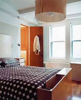 The master bedroom has a custom ramp for the dachshund at the foot of the bed and an oversize birch-veneer pendant lamp. The bedside tables are actually CD cases affixed to the wall.