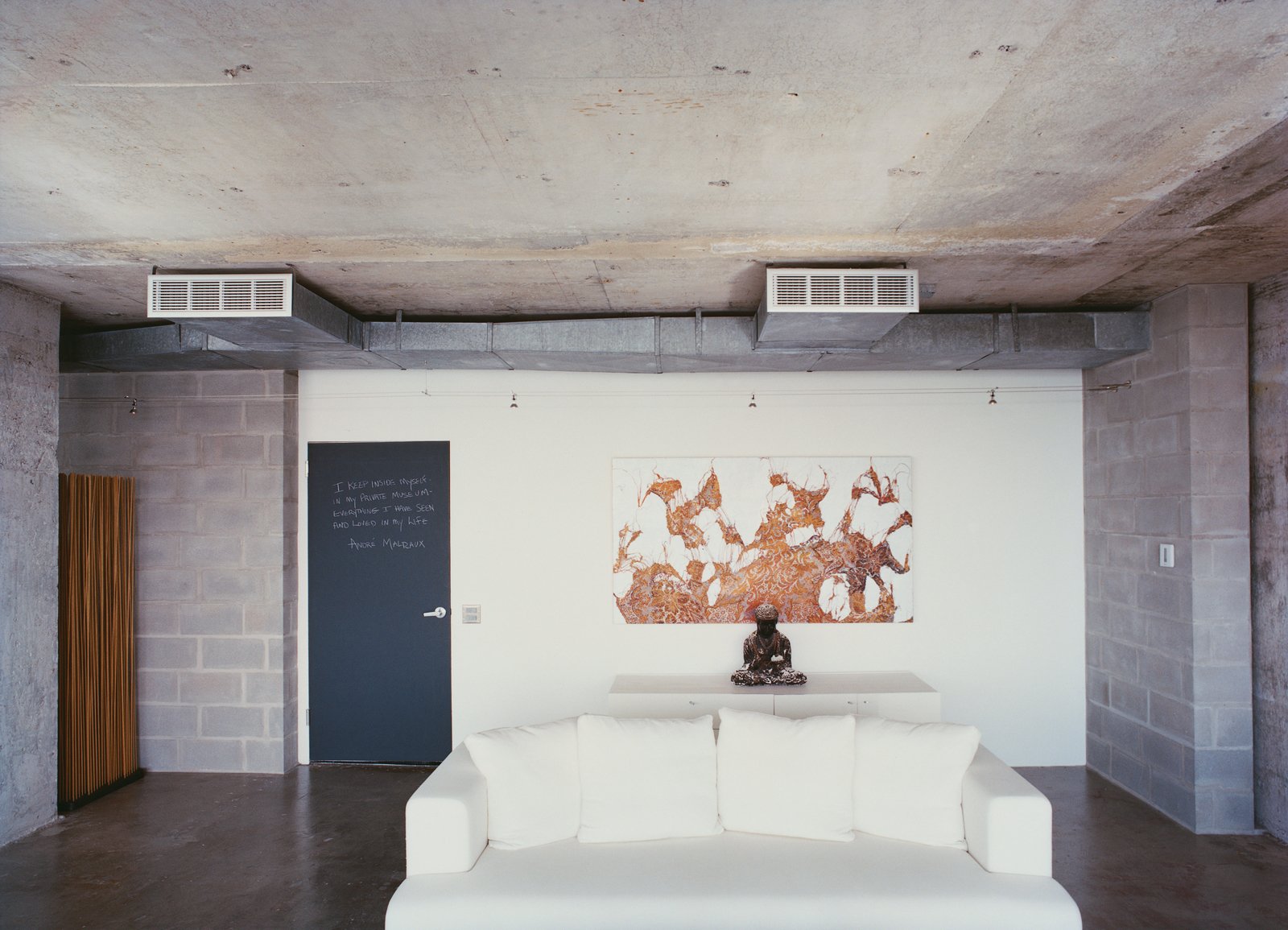 The words of the prophets are written on the chalkboard-paint-coated door to Hill's apartment. A painting by Mark Flood hangs behind a plaster Buddha on a chest from Cassina. The Ligne Roset cotten sofa was bought on sale.