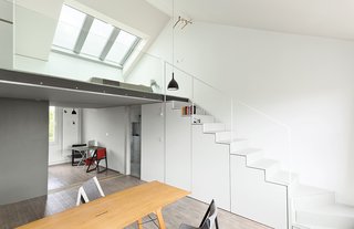 This Is How You Can Live Large in a Small Space - Photo 2 of 9 - Hynam designed and built the cabinets under the stairs and a drawer that slides out from beneath the bottom step. Drink H1 pendant lamps from Rotaliana hang in the kitchen and above a Grassworks dining table by Jair Straschnow.