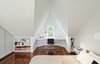 Modern home with bedroom, bed, chair, table lighting, and medium hardwood floor. “I love the master bedroom, with the geometry of the white-painted, angled roof lines and the varying shadows that this creates,” Dubbeldam says. The naturally lit space features built-in shelves and a floating desk that overlooks the street below through a tiny window. An aluminum Eames task chair and a Serge Mouille wall light adorn the space. Photo 7 of Contrast House