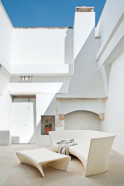 Modern Meets Ancient in a Renovated Italian Vacation Home - Photo 5 of 8 - A mix of polyethylene seating and rustic stonework is in the home's courtyard.