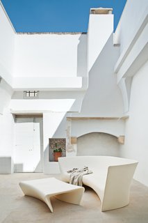 A mix of polyethylene seating and rustic stonework is in the home's courtyard.