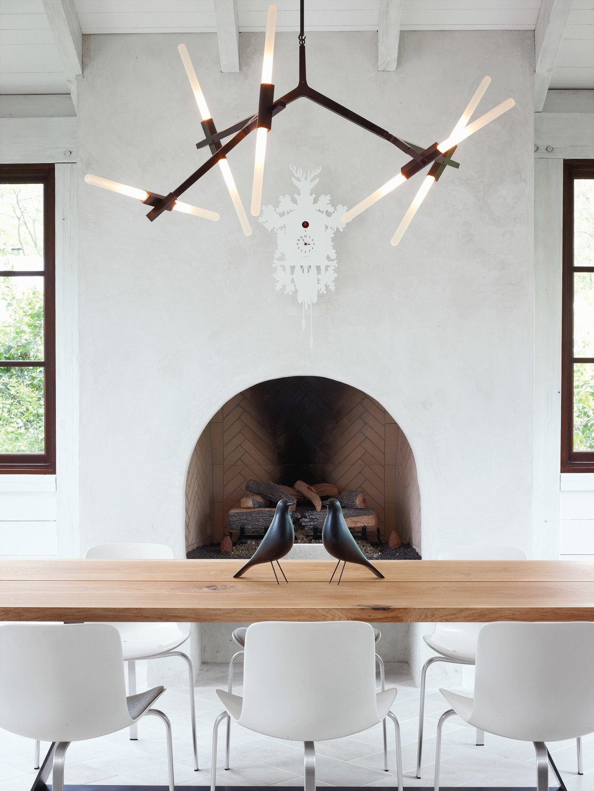 The home?s informal dining space has a slightly rustic feel, sporting bronze and wood in the form of a Lindsey Adams Adelman chandelier for Roll &amp; Hill and a table by Terry Dwan, mixed with folk-art touches like the Eames House Birds and a cuckoo clock from Diamantini &amp; Domeniconi. The PK8 chairs from Republic of Fritz Hansen were designed by Poul Kj?rlholm and sourced from Kuhl-Linscomb in Houston, Texas.