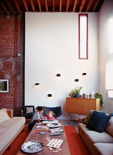 A House Grows in Brooklyn - Photo 1 of 5 - Darcy Miro and her son, Lucien, enjoy a moment in their new double-height living room. The Charlotte Perriand wall sconces are vintage finds.