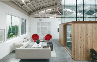 A renovated warehouse fuses engineering and artistry, much like its owners. Hutchins and Montague furnished their living area with Theatre sofas by Ted Boerner for Design Within Reach and Womb chairs by Eero Saarinen for Knoll. The Kubo coffee table is by Mobital, and the Strind side table is from Ikea. Torrent, an ink-on-watercolor-paper installation by Hutchins, hangs on the far wall.