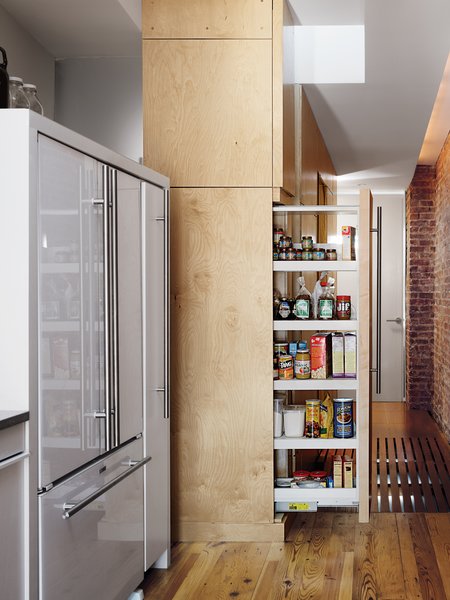 The sliding pantry cabinet doubles as a room divider when fully extended, separating the kitchen from the bedrooms.