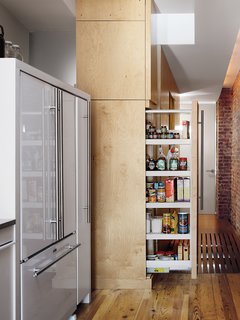 The sliding pantry cabinet doubles as a room divider when fully extended, separating the kitchen from the bedrooms.