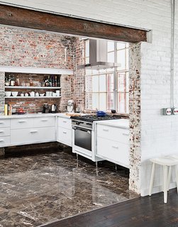 Among the couple’s cost-saving measures was outfitting the kitchen with their own custom cabinetry. The brick and windows are original, the Garland stove was a Craigslist find, and the floor tile was found on closeout at a cost of about $1 per square foot.