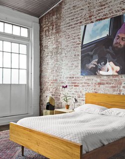 In the guest bedroom, a painting by Monique Crine hangs on the original brick wall above a Miles & May bed and side table. The rug is from ABC Carpet & Home.