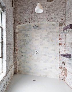 The bathroom evokes the building’s industrial bones. The pendant light is from Ikea, and the towel racks are repurposed train car luggage racks. The Carrara tiles are mismatched seconds. "It works if you let yourself not try to fix it," says Brandon.