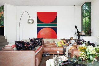 A Concrete Home in Rural Belgium - Photo 7 of 9 - De Poorter lowered the living room floor by about three feet to allow for larger windows. Vintage Sade sofas, purchased in Berlin, join an Arco lamp by Achille Castiglioni for Flos, a Noguchi coffee table, and a painting by family friend Hugo de Clercq.