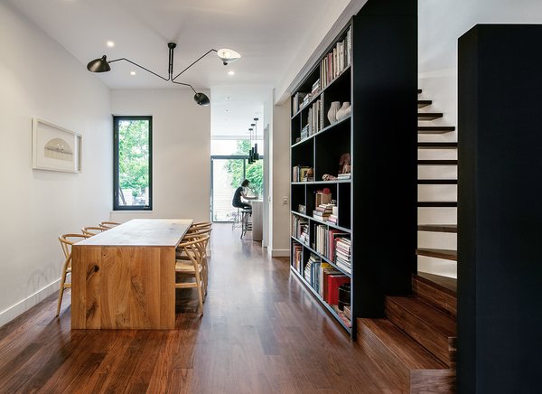 The architects created the illusion of more space by opening up the floor plan, repositioning the staircase and introducing sight lines to the large windows on the south side. Recurring black accents—from the dining room’s Serge Mouille light fixture to its tall bookcases—contrast the brightness of the crisp white walls. Walnut floors and lighter wood furniture like the Klaus Willhelm table and Hans Wegner Wishbone chairs cozy up the home, while colorful objects animate it. “We strongly believe that people do not need more space, they just need better-designed space,” Dubbeldam says. Photo 2 of Contrast House modern home