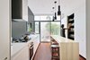 Modern home with kitchen, engineered quartz counter, medium hardwood floor, pendant lighting, range hood, and range. The architects knocked out the kitchen’s back wall, where a single window had formerly let in a miniscule amount of light, and installed sliding glass doors instead. A soothing charcoal accent wall anchors the bright white cabinetry and Corian countertops, while pendant lights by Alvar Aalto hang above an oak island. The fixtures are from KWC, Dornbracht, and Catalano. Photo 3 of Contrast House