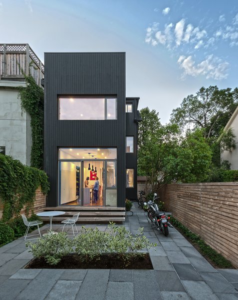 The team carried the concept of contrast through the exterior, juxtaposing the home’s 125-year-old red brick façade with vertical, black-stained cedar cladding at the back. “We wanted to celebrate the old alongside the new,” Dubbeldam says. Since the house is so well insulated, the extra heat that dark exteriors typically draw doesn’t penetrate beyond the boards’ surface. Photo 8 of Contrast House modern home