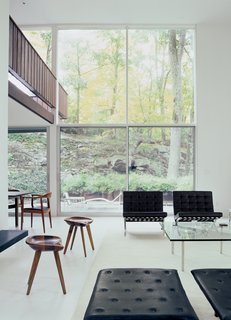 The second-floor bridge that leads to the front door flows from the outside in. "Tractor seat" stools designed by Bassam perch on a floor of pristine white terrazzo.