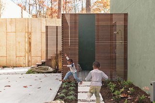 An outdoor shower in the lower courtyard includes most of the materials that define the project, including Cor-Ten steel posts, horizontal ipe slats and decking, a custom seat and towel shelf set into a natural boulder, and concrete pavers. The yard includes many elements built for play, like a water feature embedded in a concrete wall that is fed by runoff rainwater collected from the breezeway roof.