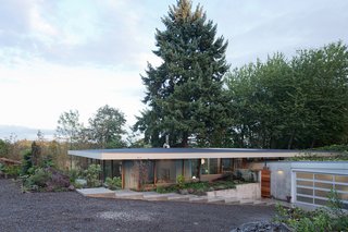 The driveway leads down a gentle slope to the garage, which is partially tucked into the earth, covered by a green roof, and fronted by a ramp leading to the entrance. Alexander Prideaux of Aurora Landscape helped integrate the house with the site.