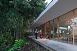 Surrounded by a canopy of trees, the house is bordered by a deep overhang that matches the width of the concrete terrace. "What I like is that the decks and the courtyard are visually part of the house, but they’re outdoor spaces," says Ted. Heid worked with Curtis Bosworth and John Weed of WBS Construction on the project.
