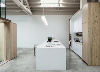 This Light-Filled Industrial Renovation Plays Host to Live Music - Photo 4 of 11 - A custom light fixture by the Sterling Steel Company hangs over the quartz countertop by Caesarstone. The clear Douglas fir doors on the cabinets were whitewashed to let the grain shine through.