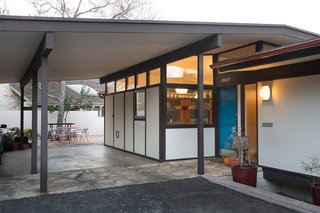 A close-up of the renovated exterior shows the home's new, brightly-colored door in relief of the new kitchen window, whose floating shelves are just visible. Selected by Sloan Houser, the door's shade of turquiose is similar to Benjamin Moore's Americana, although with stronger hints of green.