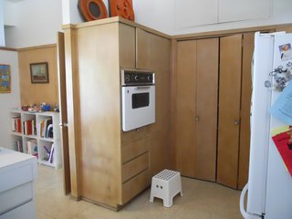 BEFORE: Prior to renovation, low-contrast wood cabinets obstructed the passage between the kitchen and the family room, giving both rooms a feeling of dullness in spite of the light tone of the wood and the walls around it.