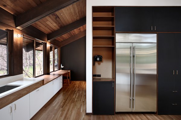 The kitchen was originally an awkward alcove facing the main living area. The architects expanded the room and installed a classic modernist ‘service core’ at the kitchen’s center; it features large appliances such as a Sub-Zero fridge and an Asko washer/dryer. This allows easy movement through the kitchen to the adjacent dining room and main hallways. Photo 3 of Zema Redux modern home