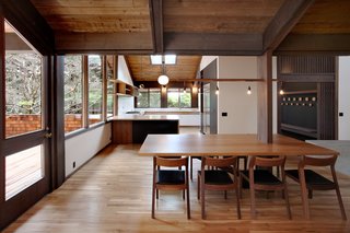 A renovated 1970s house in Washington features a string of dangling lights above the dining table. The table previously had an awkward placement around a column. For a more efficient solution, the architects simply embedded the table in the column, using carefully selected wooden supports that would match existing tones. 