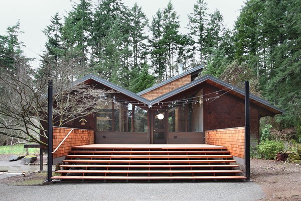The architects added an extended deck that creates an opportunity for gatherings. It also smoothly transitions the interior level, which hovers above the ground on pylons, back to the earth. Steel columns were specially implemented so the clients could string lights over the deck. A fire-pit is now located in front of these steps. Photo 10 of Zema Redux modern home