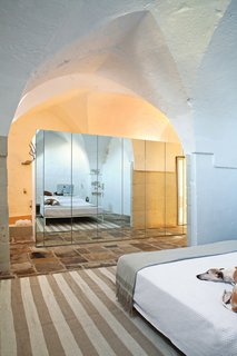 The house gracefully marries modern and ancient, as seen in the master bedroom, where a custom-built mirrored storage unit divides the sleeping and bathing areas.