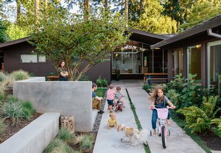 In their concrete-walled courtyard, Yuka and Aaron watch as twins Emerson and Jasper, daughters Maude and Mirene, and Alfie the dog play. The house is painted in Black Bean Soup by Benjamin Moore, a color in keeping with the period of the original architecture
