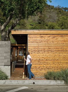 Flanking the concrete wall is a carport and an entrance leading past a small, cedar-clad ancillary building for art projects and laundry.