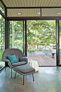 Saarinen Womb Chair upholstered in Knoll fabric is accented by a Maharam pillow and a ceramic Oppiacei pouffe from Skitsch. Acapulco chairs, handmade by Greenpoint Works in Brooklyn, and a Prince Aha stool by Philippe Starck for Kartell grace the deck outside. Photo by: Kimberly Davis