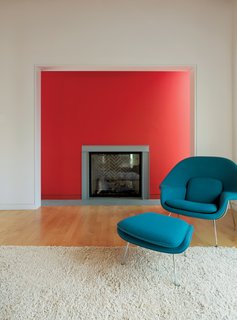 Family Matters - Photo 14 of 16 - In the living room, Fashandi enjoys lounging in the Saarinen Womb chair by Knoll near the fireplace. The red wall is flanked by thin windows, causing it to glow in the sunlight.