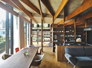 In the open living and dining room of a hillside family home in Japan, Eames shell chairs surround a custom walnut table by Kagura. The upholstered seating is by Arflex. The architect, Masahiro Harada of Mount Fuji Architects Studio, also designed the custom kitchen island and stove vent.