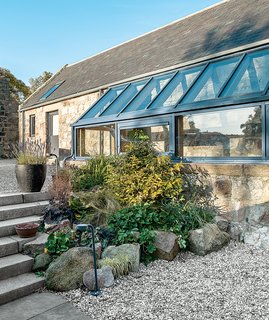 This Farmhouse is a Cor-Ten Steel-Clad Dream - Photo 10 of 11 - The glass balustrade and floor were sourced in Germany and installed by James Aiken. Angelique, the founder of Papillon Designs and Landscaping, clustered plantings around the exterior glass addition.