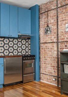 A Gut Renovation Transforms a Tiny Manhattan Apartment - Photo 4 of 8 - "In the kitchen, we changed the layout," Davison says. "It was a galley kitchen, extending lengthways into the room. We spun it back along the back wall. The tiles are Moroccan concrete tiles that came from a supplier here in Manhattan. The idea was to inject some color and playfulness into the space with the blue cabinetry." Photo by Alan Gastelum.