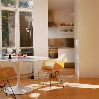 Garage Brand - Photo 3 of 8 - The kitchen spills out into the living room, where the focus is on a Saarinen Tulip table, Eames fiberglass shell chairs, and lamps by Achille Castiglioni.