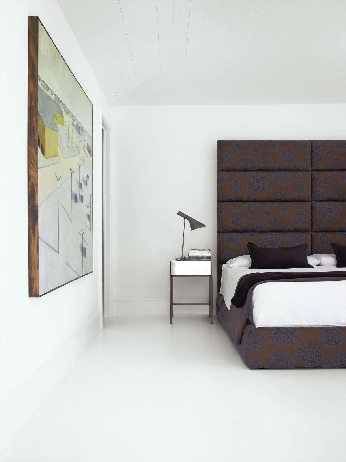 Intended for a much bigger room in the family?s previous home, the bed was designed by Hill and is covered in Maharam fabric in a doily print called Intricate 001 Charcoal. The side tables are from West Elm, and the AJ table lamp is by Arne Jacobsen for Louis Poulsen.