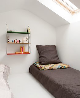 A colorful shelf offers bedside storage in a London guesthouse.
