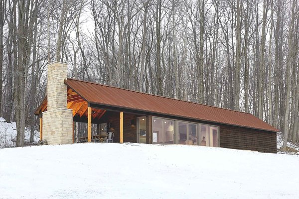 The retreat’s southern exposure maximizes sunlight with 24 feet of floor-to-ceiling windows. The sun’s warmth is absorbed and stored in the concrete floor, keeping the interior warm. Combined with thickly insulated walls, the cabin requires little additional energy, and has gone up to three days in winter without any electrical heating. Photo 3 of Off-Grid Retreat modern home