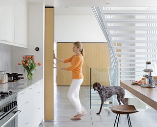 A Minimalist Duplex in Venice, California - Photo 4 of 9 - A nine-foot-tall door covered with quarter-inch white oak slides along a ceiling rail and can be moved with just a finger to close off Don and Lisa’s kitchen or bedroom. Made of wood and metal, and welded onsite, the door moves along 400-pound-capacity rollers by McMaster-Carr. A matching sliding door opposite hides a storage area. "Because of their size, the doors had to be made inside," says Don, who did the job himself.