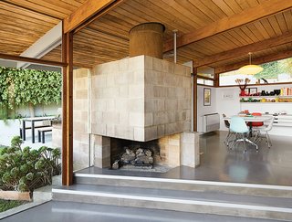 A Midcentury Home Keeps the History Alive - Photo 3 of 10 - The dining area features a distinctive cinder block fireplace. Molded plastic side chairs are arranged around a Segmented Base table, all by Charles and Ray Eames for Herman Miller. The space is illuminated by a Saucer pendant lamp by George Nelson from Modernica.